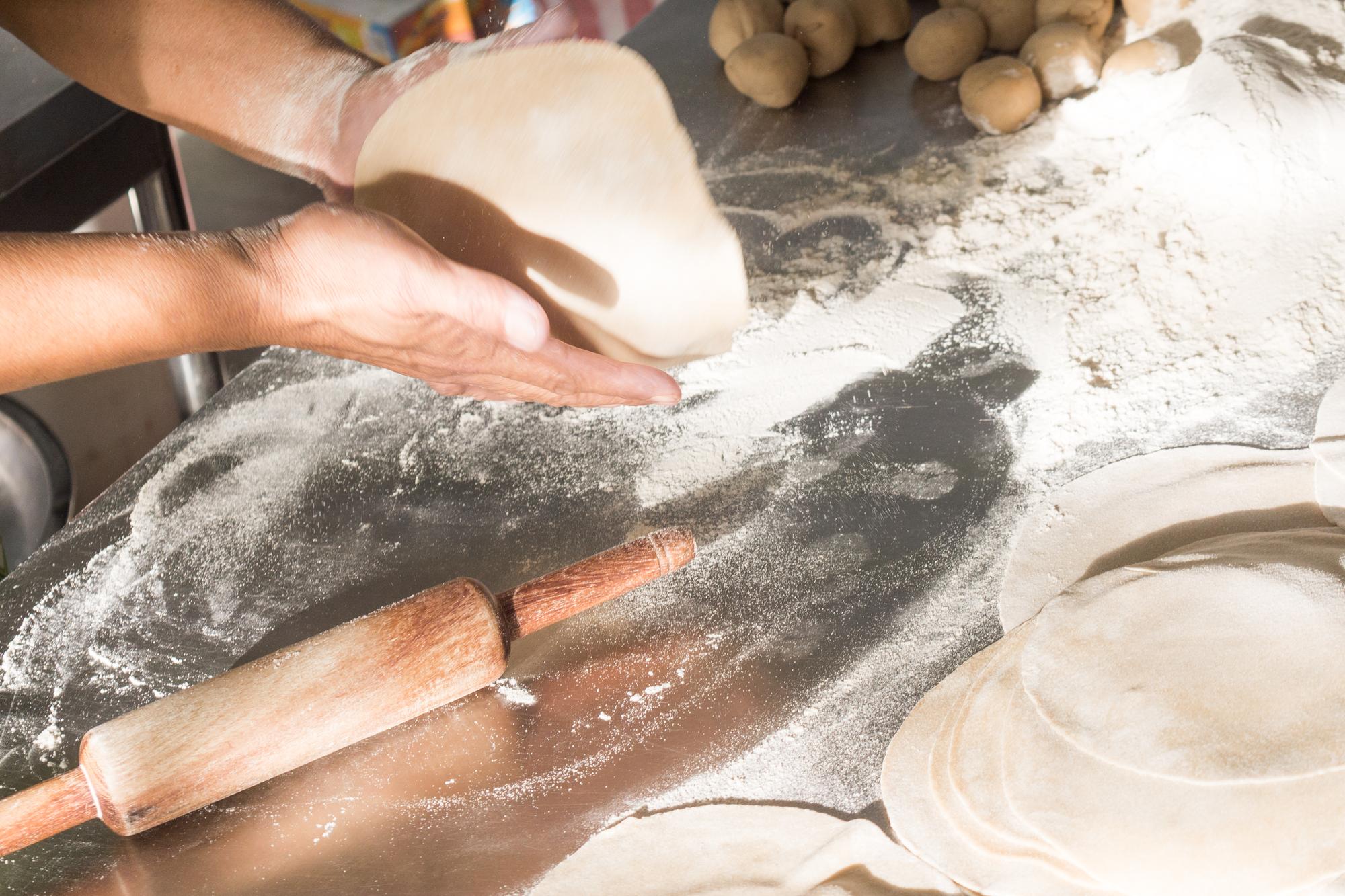 hands stretching dough on a floured board